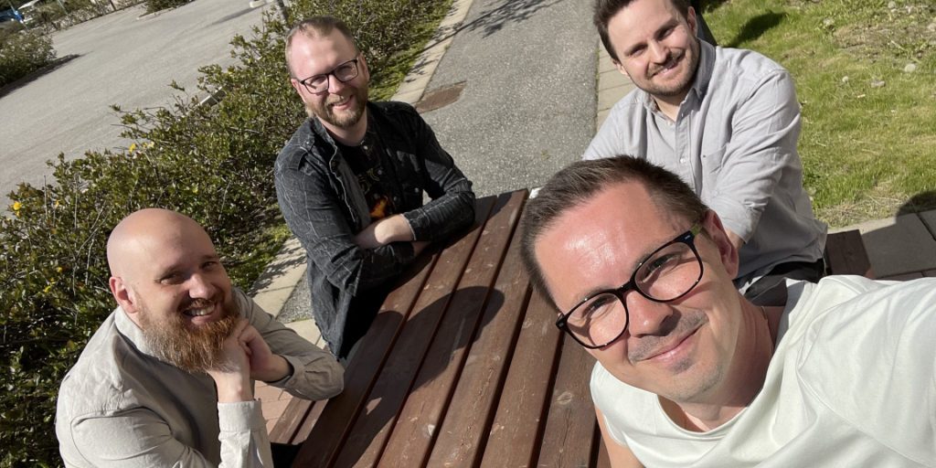 Linus Ström, Joel Jonasson, Patrik Knutsson, Rickard Jäger från Blast Bit vid ett bord i sol.